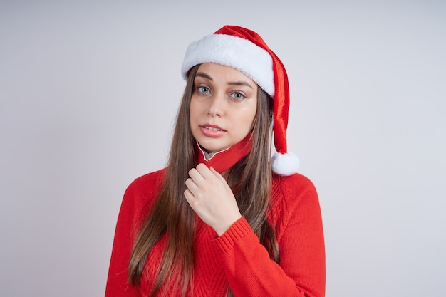 Woman in santa hat, red sweater, choking removes a protective\
mask