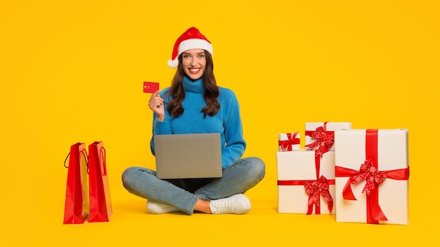 Woman in santa hat with credit card and laptop studio