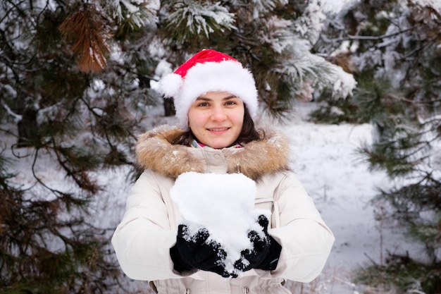 A woman in Santa's hat holds a snowball in her hands