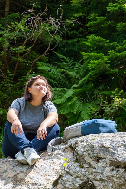A woman sat down to rest on a rock in the forest