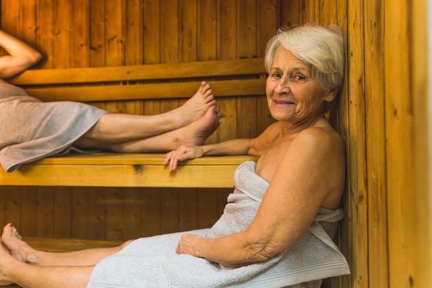 A woman in a sauna with a woman in a towel
