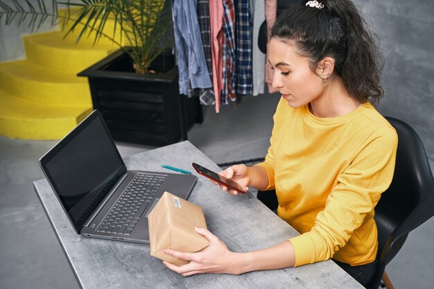 女性は携帯電話のカメラを使用して小包のコードをスキャンします