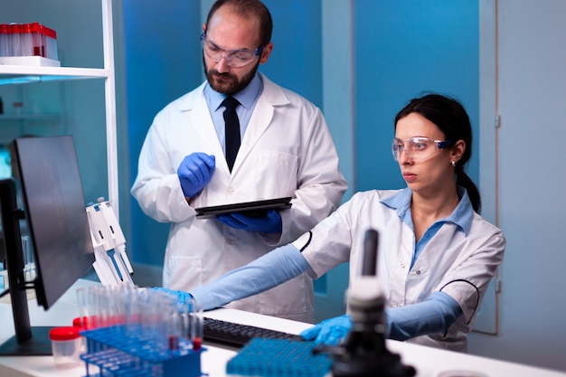 전문 기술 장비를 사용하는 의학 실험실에서 바이러스 전문 지식을 연구하는 여성 과학자 및 남성 의사