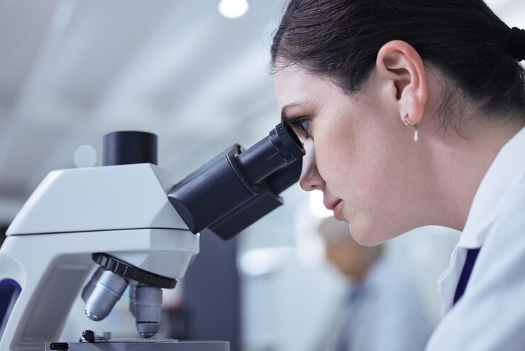 Photo woman scientist microscope and medical research in chemistry lab for science experiment in medicine female person innovation and test for pharmaceutical study pathology or mpox vaccine in denmark