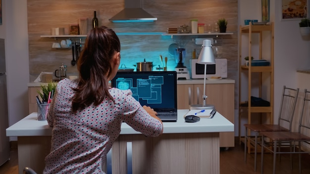 Woman scrolling programming security hacking code data late at night on laptop. Programmer writing a dangerous malware for cyber attacks using performance device during midnight.