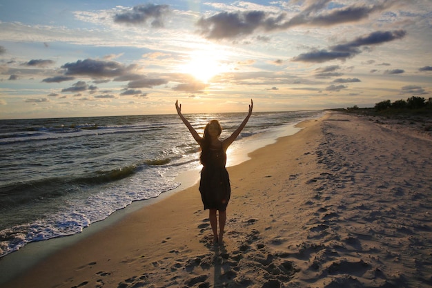 Woman on the sea coast on sunset