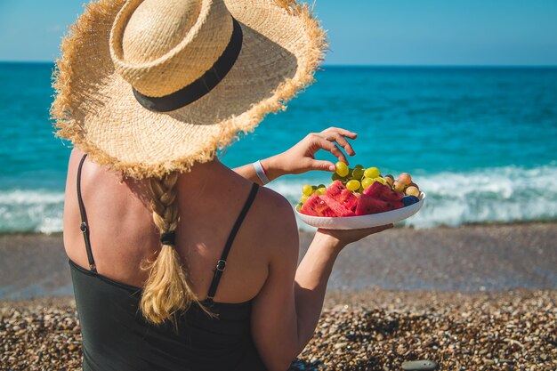 A woman at the sea eats fruit. Selective focus.