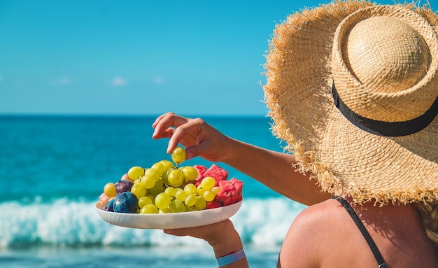 Foto una donna al mare mangia frutta. messa a fuoco selettiva.