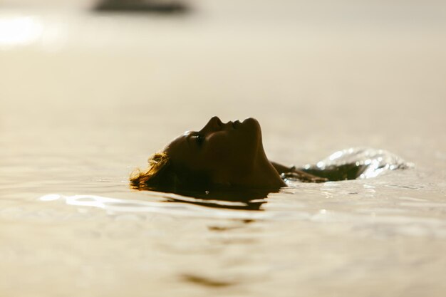 Woman in sea water on sunset