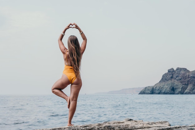 Woman sea yoga back view of free calm bliss satisfied woman with long hair standing on top rock with