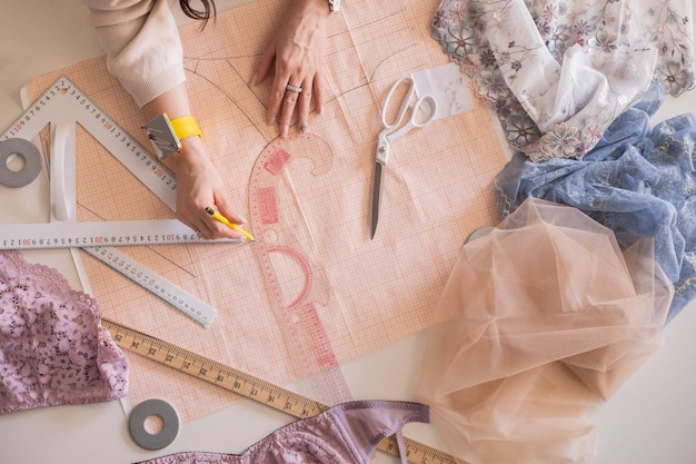 a woman seamstress designs and draws a pattern for underwear on graph paper