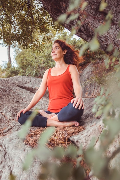 Woman seated in lotus position on rock