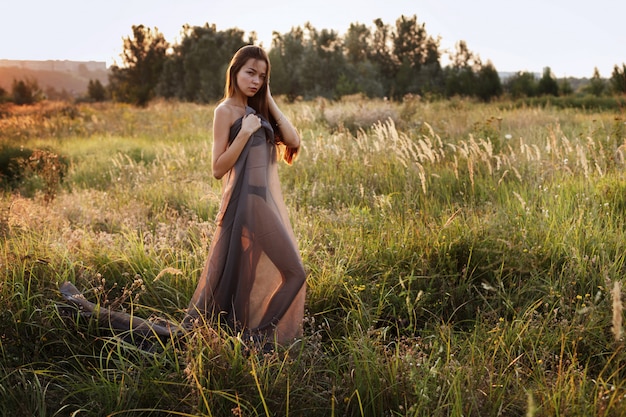 Woman in a see-through summer dress at sunset