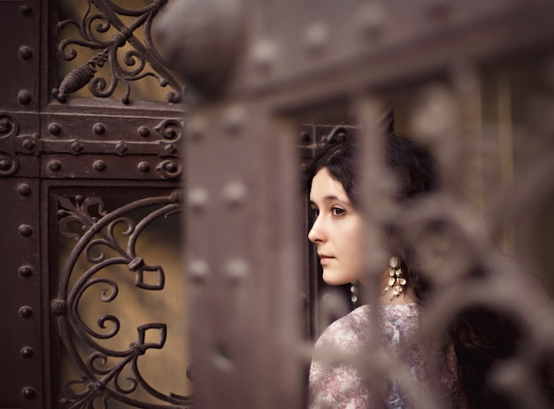 Woman seen through the fence of a door