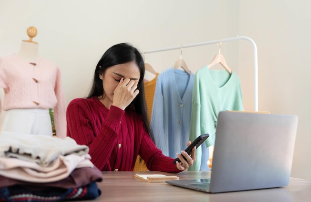 Woman seller SME retail store owner work hard worry stress in bad news on laptop at home office desk Asian people crisis tailor job issue feel tired tough and upset in cash money loss or loan debt