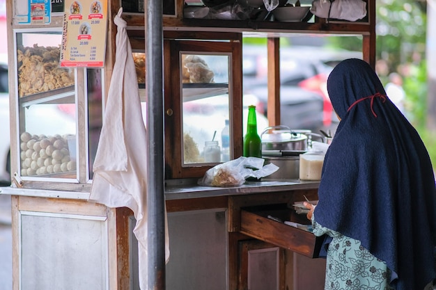 Photo a woman selling bakso a popular local meatball soup on roadside