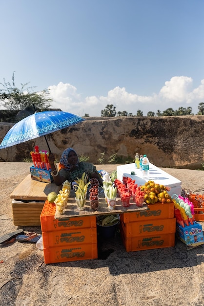 A woman selling fruit and juices at a roadside stand.