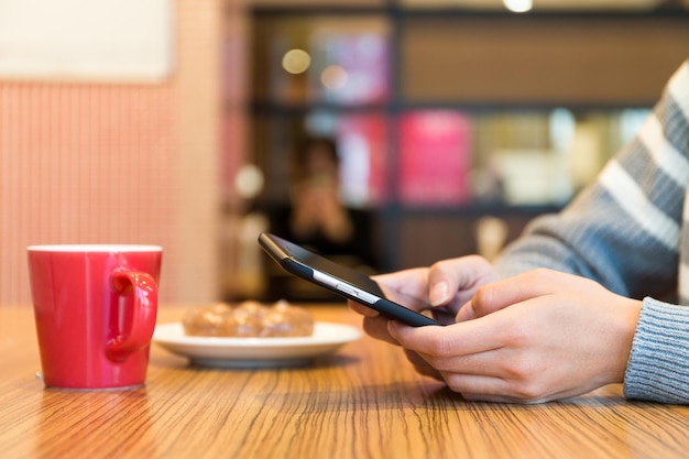 Woman sending sms on cellphone in cafe