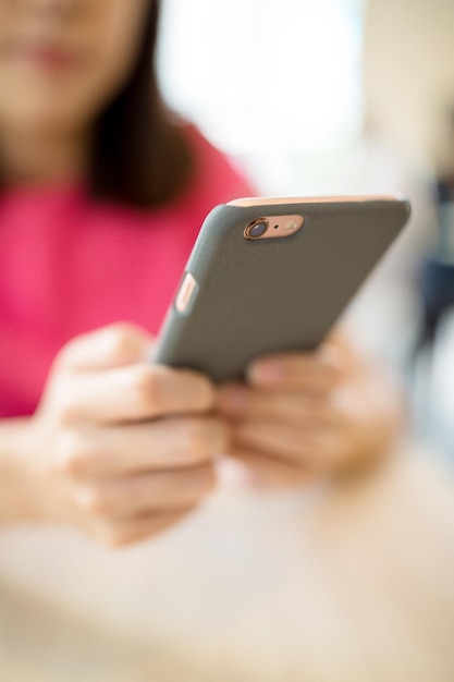 Woman sending sms on mobile phone in coffee shop