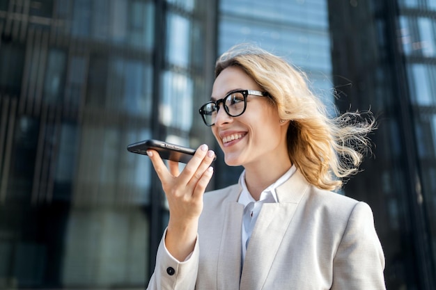 A woman sends a voice message to a client by email using a phone Glasses on his face goes