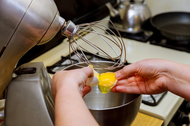 Woman separates egg whites from yolk in mixer bowl