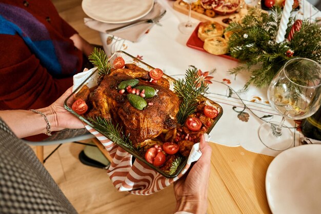 a woman serves a roasted turkey during a christmas family dinner on new year's eve