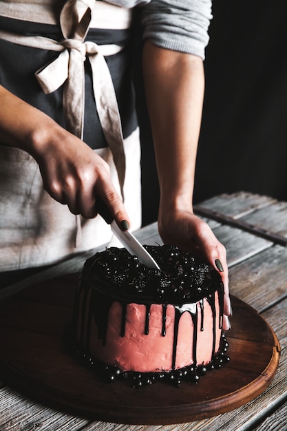 Woman serving delicious cake into slice