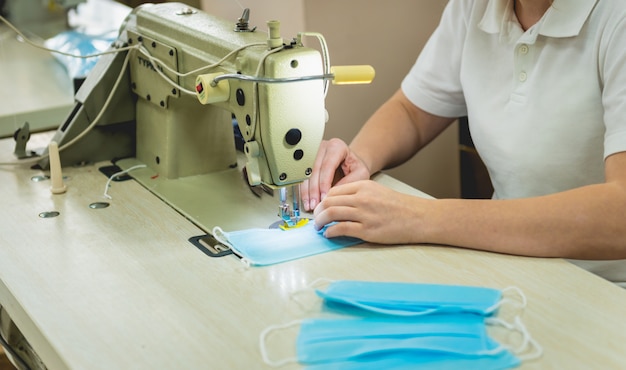 Woman sew the facial medical at sewing machine. Coronavirus pandemia.