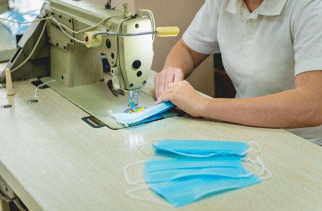 Woman sew the facial medical at sewing machine.