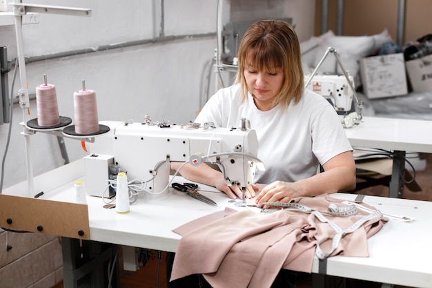 Woman sews on sewing machine at factory