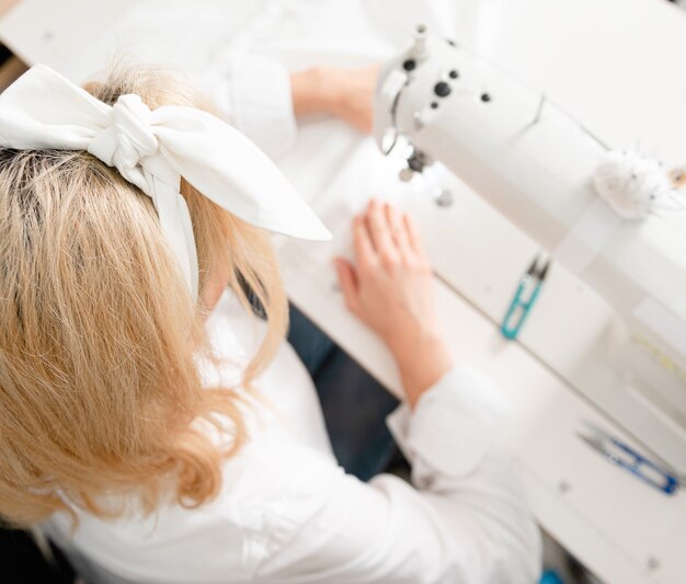 woman sews on a sewing machine sitting at the table Hobby handicraft profession skills