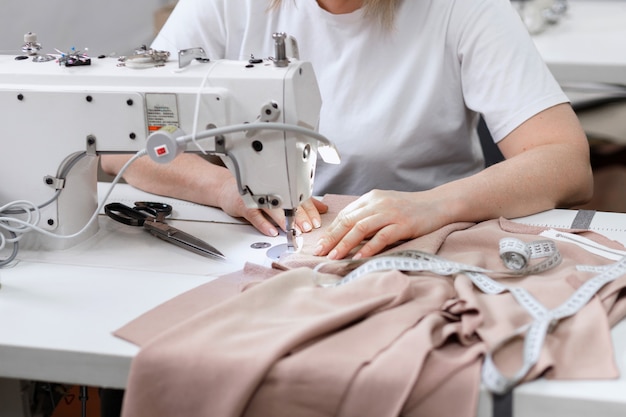 Woman sews behind sewing machine at work