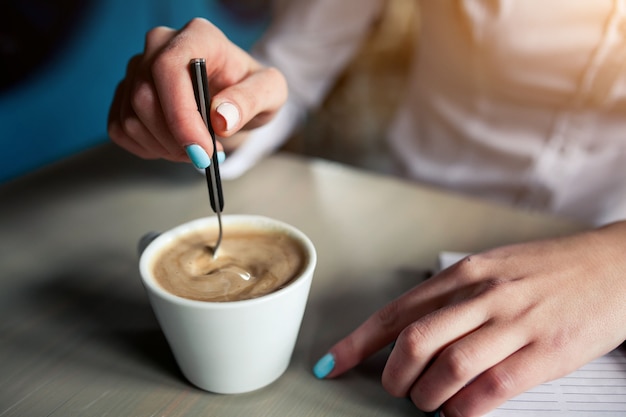 ティースプーンでコーヒーを振る女