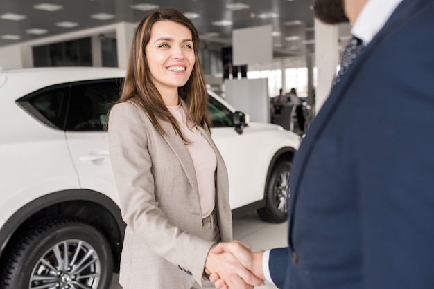 車のセールスマンと握手する女性