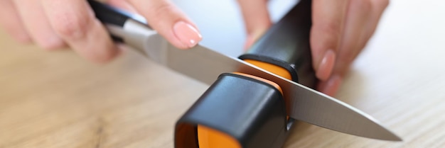 Woman sharpens knife with sharpener in kitchen closeup Woman doing men's work concept