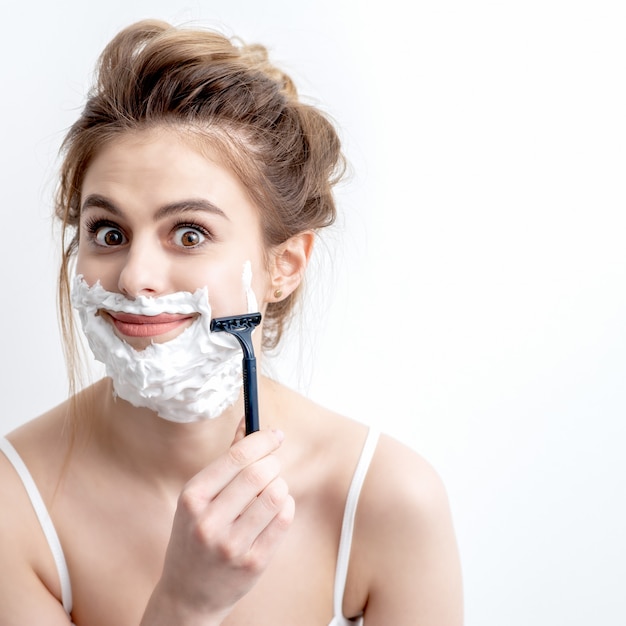 Женщина бреет лицо бритвой