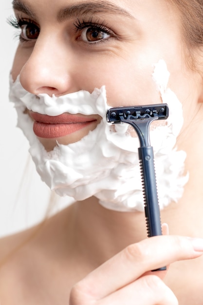 Woman shaving her face by razor