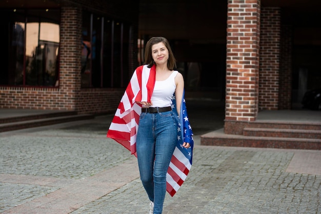 Foto donna protetta dalla bandiera americana che sorride e celebra il giorno dell'indipendenza del 4 luglio