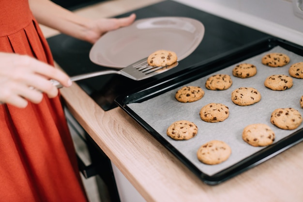 Woman shifts freshly baked cookies from pan onto plate