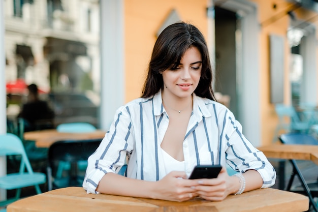 Woman in shirt looks at phone