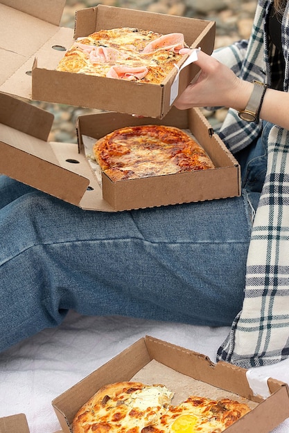 A woman in a shirt with a checkered pattern near the river eats
ready-made pizza with appetite