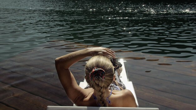 スマートフォン用のハンドヘルドフィルムジンバル安定化で撮影している女性女の子の休息は桟橋に日光浴で横たわっています