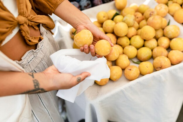 Donna che fa shopping per l'albicocca, compra al mercato della frutta fresca