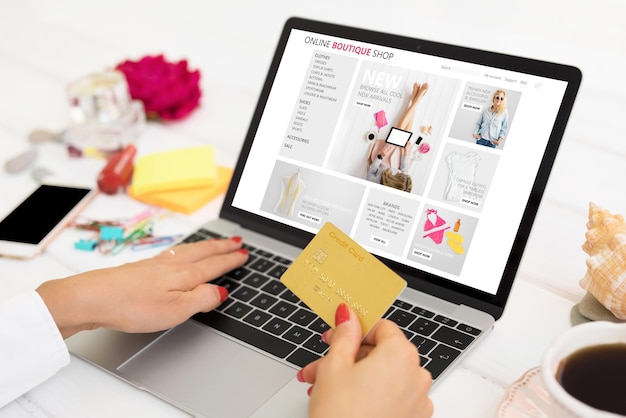 Woman shopping online on her laptop and holding credit card in hand