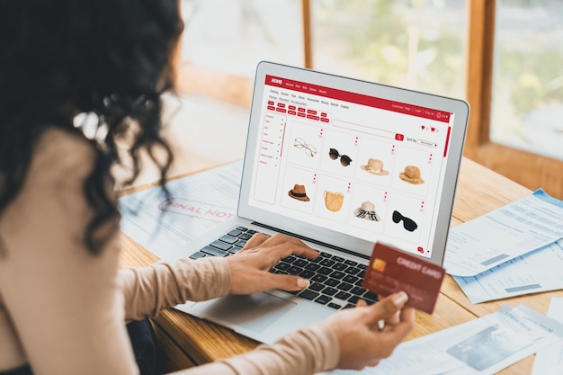 인터넷 시장에서 온라인 쇼핑을 하는 여성은 현대적인 라이프스타일에 맞는 판매 품목을 검색하고 중요한 사이버 보안 소프트웨어로 보호되는 지갑에서 온라인 결제를 위해 신용 카드를 사용합니다.