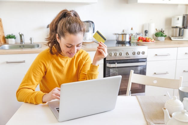 Woman shopping online and paying with gold credit card