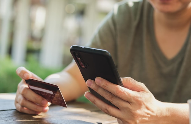 Woman shopping online with credit card at coffee shop in outdoorclose up hand holding smartphone