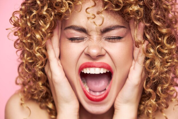 Woman Shouts and covered her ears with her hands red lips pink background