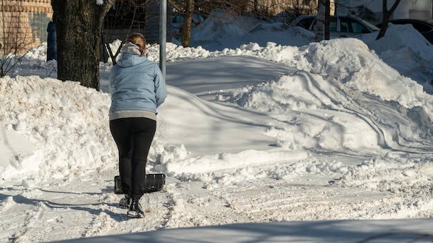 Женщина сметает снег с тротуара.