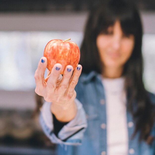 Photo woman showing an apple in her kitchen